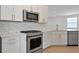 Modern kitchen features white cabinets, quartz countertops and stainless steel appliances at 25917 Bimini Sands Ct, Englewood, FL 34223