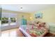 Cozy bedroom with yellow walls, wood floors, a colorful bedspread, and a window overlooking the backyard at 409 Pine Ave, Anna Maria, FL 34216