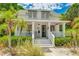 Charming two-story home with a covered front porch, awning covered windows, and lush tropical landscaping at 409 Pine Ave, Anna Maria, FL 34216