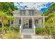 Charming two-story home with a covered front porch, awning covered windows, and lush tropical landscaping at 409 Pine Ave, Anna Maria, FL 34216