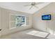 Bright bedroom with window shutters, ceiling fan, and wall-mounted TV at 6723 Approach Rd # 35, Sarasota, FL 34238