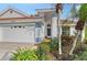 House exterior featuring a white facade, two-car garage, and tropical landscaping at 6723 Approach Rd # 35, Sarasota, FL 34238