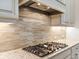 Gas cooktop with modern range hood and stylish backsplash at 7220 Whittlebury Trl, Lakewood Ranch, FL 34202