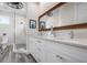 Bathroom featuring white cabinets, double sinks, a large mirror, and a walk-in shower at 915 N Shore Dr, Anna Maria, FL 34216