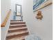 Beige carpeted staircase with wooden railing and wall decor at 10031 Crooked Creek Dr # 201, Venice, FL 34293