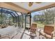 Relaxing screened-in patio with tile flooring, ceiling fan, and beautiful view of the landscaped backyard at 2218 Shadow Oaks Rd, Sarasota, FL 34240
