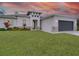 White house with gray roof and dark gray garage door, landscaping and lawn at 2692 Mctague St, North Port, FL 34291