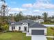 White house with gray roof and dark gray garage door, landscaped lawn at 2692 Mctague St, North Port, FL 34291