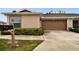 Front view of a tan house with a brown garage door and neatly landscaped yard at 2906 Captains Ct, Palmetto, FL 34221
