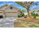 Tan house with a two-car garage, stone accents, and a landscaped yard at 4914 Lakescene Pl, Sarasota, FL 34243