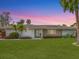 Single-story home with a stone accent wall, lush landscaping, and a tranquil sunset backdrop at 5560 Shadow Lawn Dr, Sarasota, FL 34242