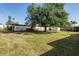 Expansive backyard with lush green grass, mature trees, and a storage shed against a white fence at 807 62Nd W St, Bradenton, FL 34209