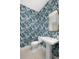 Stylish powder room with patterned wallpaper and pedestal sink at 9985 Key Haven Rd, Seminole, FL 33777