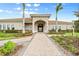 Inviting clubhouse entrance with a brick pathway, landscaping, and palm trees at 19066 Mangieri St, Venice, FL 34293