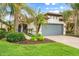 Landscaped front yard with palm trees, walkway, and a gray garage door at 19066 Mangieri St, Venice, FL 34293