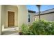 Front entryway with a brown door and lush landscaping at 221 Brindisi Cir, Nokomis, FL 34275