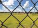 View of a soccer field through a chain link fence under a partly cloudy sky at 4590 Oakley Rd, North Port, FL 34288