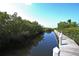 Wooden dock extending into tranquil waterway lined with trees at 5531 Cannes Cir # 802, Sarasota, FL 34231