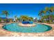 Inviting community pool with a center island feature surrounded by lounge chairs and palm trees at 7005 River Hammock Dr # 301, Bradenton, FL 34212