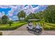 Golf cart parked on a paved path, showcasing the lush green golf course and blue skies at 7703 Whitebridge Gln, University Park, FL 34201