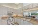 Bright kitchen featuring white cabinets, tiled backsplash, and a pass-through window to the living area at 7703 Whitebridge Gln, University Park, FL 34201