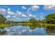 Scenic lake view with lush greenery and clear sky reflections, showcasing a serene community setting at 7703 Whitebridge Gln, University Park, FL 34201