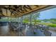 Covered outdoor dining space overlooking a lush landscape and tranquil lake, ideal for relaxation at 7703 Whitebridge Gln, University Park, FL 34201