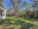 Grass backyard with mature trees and partial view of house at 11264 28Th Street E Cir, Parrish, FL 34219