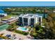 Aerial view of waterfront condo building with pool, tennis court, and parking at 3240 Gulf Of Mexico Dr # B104, Longboat Key, FL 34228