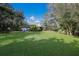 Large grassy backyard with mature trees and home view at 3395 Hardee Dr, Venice, FL 34292