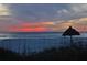 Peaceful beach sunset view with thatch umbrella at 415 L Ambiance Dr # A401, Longboat Key, FL 34228