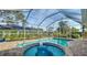 Sparkling pool and jacuzzi with brick patio, lush landscaping, and screened enclosure at 429 N Rossetti Dr, Nokomis, FL 34275