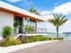 Modern waterfront building with a balcony, steps, and tropical landscaping at 6821 Longboat S Dr, Longboat Key, FL 34228