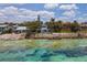 Aerial view of waterfront home with a rocky shoreline and clear ocean at 7314 Point Of Rocks Rd, Sarasota, FL 34242