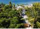 Aerial view of beachfront home nestled amongst lush tropical foliage at 7314 Point Of Rocks Rd, Sarasota, FL 34242