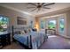 Main bedroom with large windows, golf course view, and ceiling fan at 7503 Calle Facil, Sarasota, FL 34238