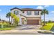 Two-story home with a brown door and attached garage, landscaping, and palm trees at 8208 Carrhill Pl, Parrish, FL 34219