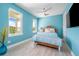 Bedroom with bright blue accent wall, ceiling fan, and large windows providing natural light at 935 Bayshore Rd, Nokomis, FL 34275