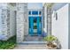 Close-up of the front door featuring stone columns, a bright blue door, and tiled porch and planter at 935 Bayshore Rd, Nokomis, FL 34275