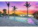 Inviting pool featuring fountains, elegant tile surround, and tranquil water views beneath palm trees at sunset at 935 Bayshore Rd, Nokomis, FL 34275