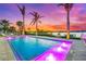 Luxurious waterfront pool features fountains, elegant tile surround, and palm trees at a vibrant sunset at 935 Bayshore Rd, Nokomis, FL 34275