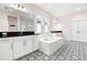 Bathroom with double vanities, a soaking tub, and patterned floor tile at 1012 Fernleaf Run, Bradenton, FL 34212