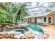 Inviting pool and spa surrounded by lush landscaping and screened enclosure at 1130 Anclote Rd Rd, Tarpon Springs, FL 34689