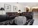 Spacious living room featuring brown leather sofas, a zebra-print ottoman, and a view into the kitchen at 3716 Eagle Hammock Dr, Sarasota, FL 34240