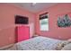 Bedroom with pink walls, floral bedding, and a flat-screen TV at 3906 Chaucer Ln, Sarasota, FL 34241