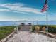 Wooden deck overlooking calm water with benches and American Flag at 4239 Gulf Of Mexico Dr # Mh4, Longboat Key, FL 34228