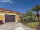 Well-maintained house with a brown garage door, landscaping, and palm trees at 5715 Spanish Point Ct, Palmetto, FL 34221