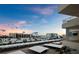 Wide angle rooftop view of parking, palm trees, neighboring buildings, and a picturesque sunset at 5780 Midnight Pass Rd # 609, Sarasota, FL 34242