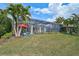 Picturesque backyard with screened enclosure, lush lawn, and tropical landscaping; ideal for relaxation at 8261 Grande Shores Dr, Sarasota, FL 34240