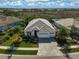 Aerial view of a beautiful single-Gathering home with lush landscaping, a paver driveway, and a three-car garage at 8261 Grande Shores Dr, Sarasota, FL 34240